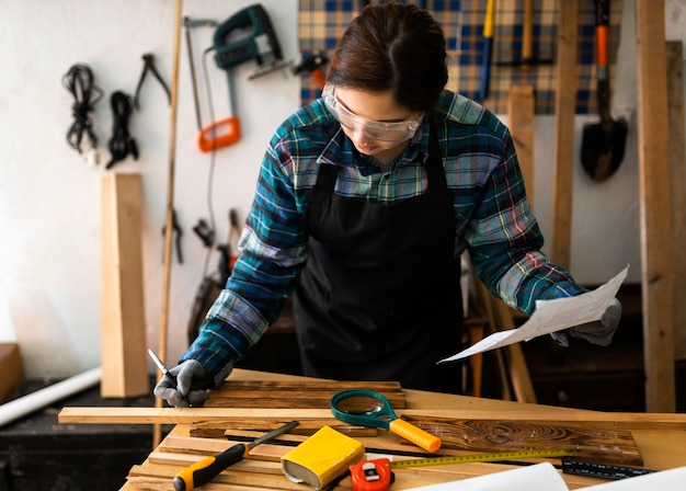 Female in workshop measure wood plank