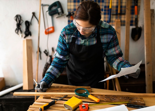 Женщина в мастерской измеряет деревянную доску