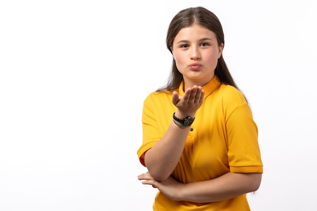 female in yellow shirt and blue jeans posing and sending air kissesion on the white background woman model clothes