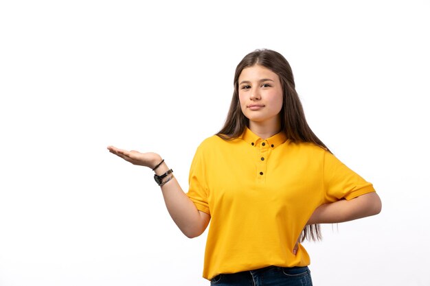 female in yellow shirt and blue jeans posing with open palm on the white background woman model clothes