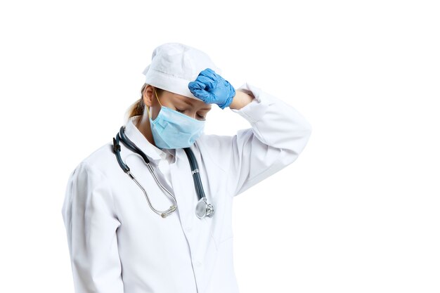 Female young doctor with stethoscope and face mask isolated on white  wall
