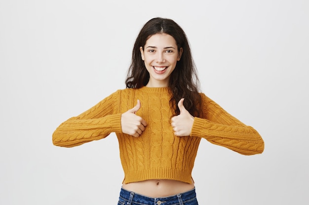 Female young entrepreneur showing thumbs-up in approval, agree or like something, praise choice