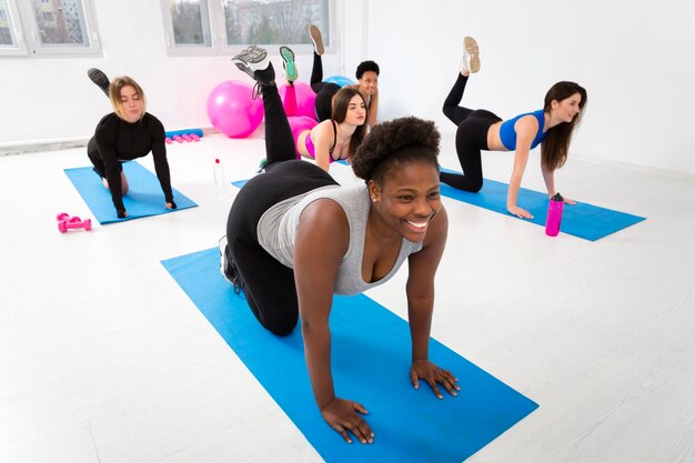 Females exercising on mat at gym