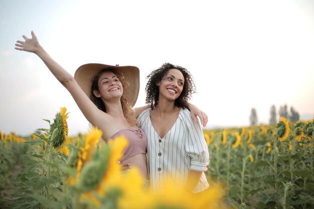 Females hugging each other surrounded by a sunflower field