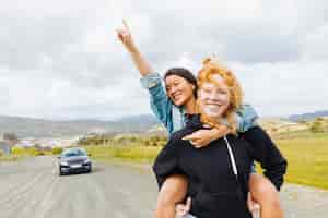 Free photo females playing piggyback near parked car