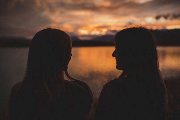 ニュージーランドのポルカ湖で日没時に海岸に座っている女性