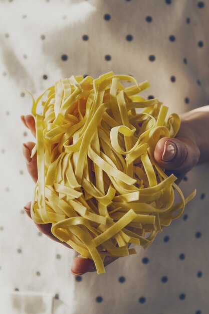 Feminine hands cook holding tasty fresh raw traditional italian pasta. Closeup. Toning.