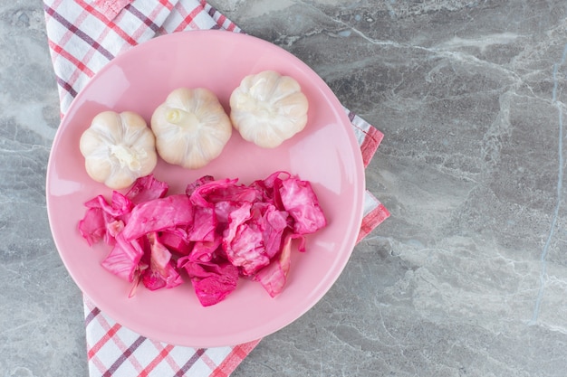 Free photo fermented cabbage. sauerkraut with pickled garlic on pink plate.