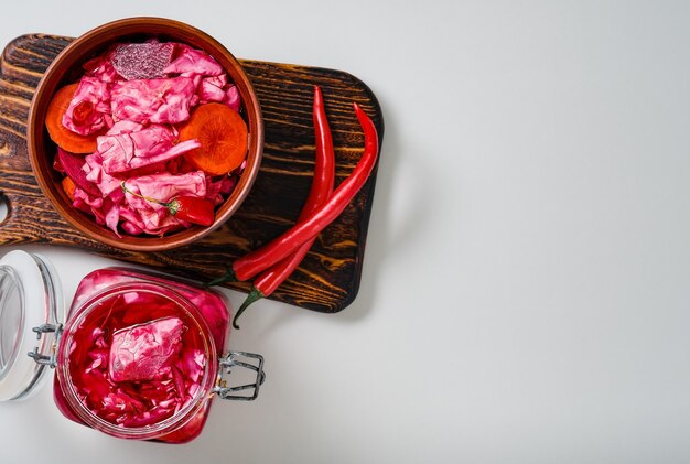 Fermented, canned vegetarian meals. Homemade pickled cabbage with beets, carrots and chili. Sauerkraut in glass jars on a gray kitchen table, top view with copy space. Food concept