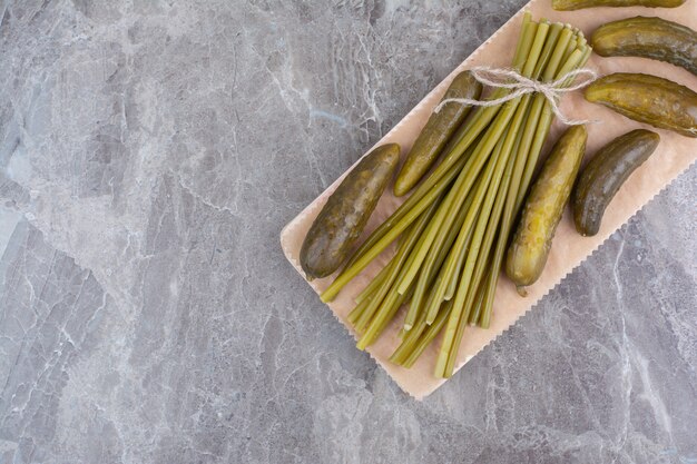 Fermented cucumbers and green beans on wooden board.