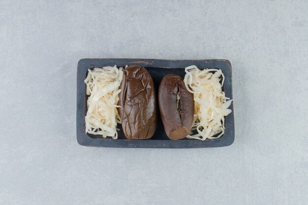 暗いプレートに茄子とザワークラウトを発酵させたもの。