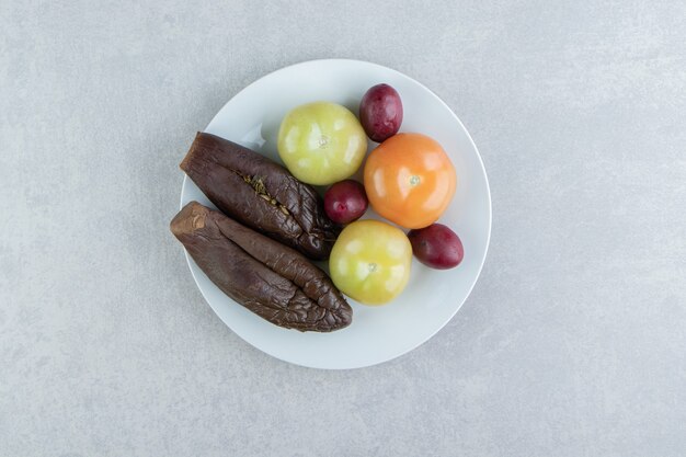 Fermented eggplant and tomatoes on white plate. 