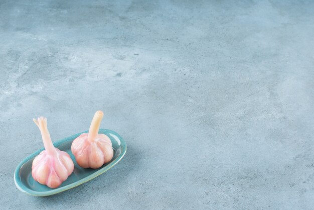 Fermented garlic on a plate on the blue surface