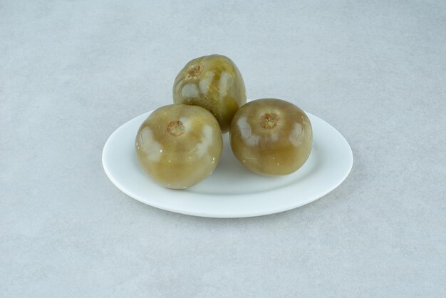 Fermented green tomatoes on white plate.