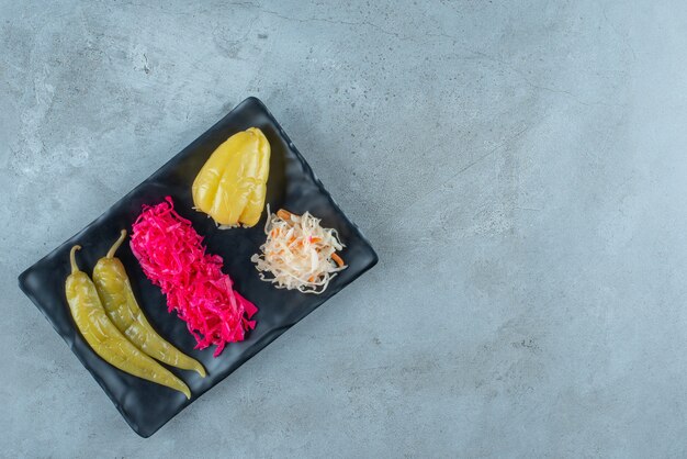 Fermented pepper and sauerkraut on a plastic plate , on the blue table. 