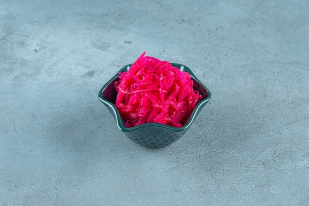 Free photo fermented red cabbage lies in a bowl, on the blue table.