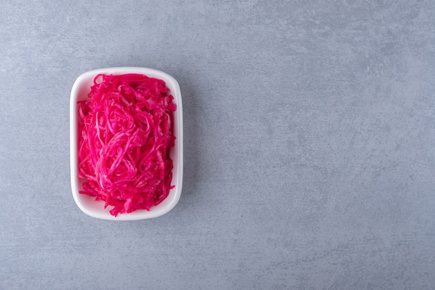 Fermented red cabbage lies in bowl , on the marble background.