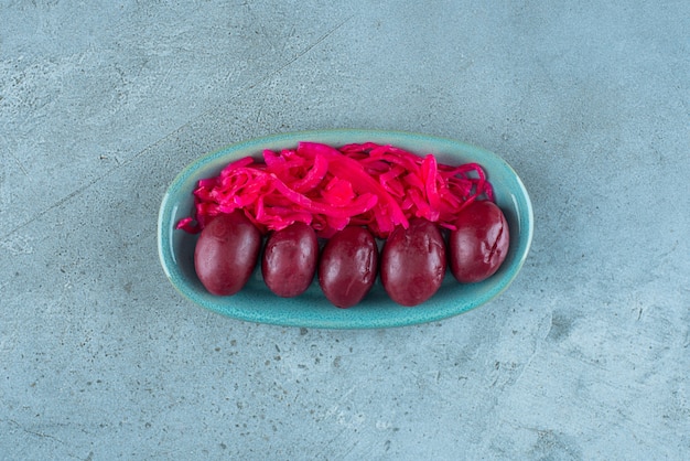 Free photo fermented red sauerkraut with plums on a plate , on the blue table.