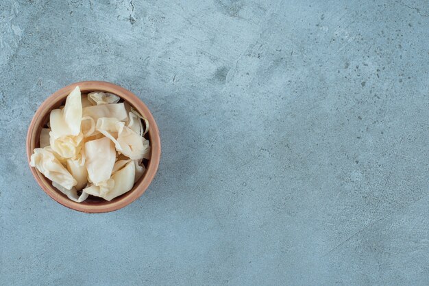 Fermented sauerkraut with carrots in a bowl, on the blue table. 