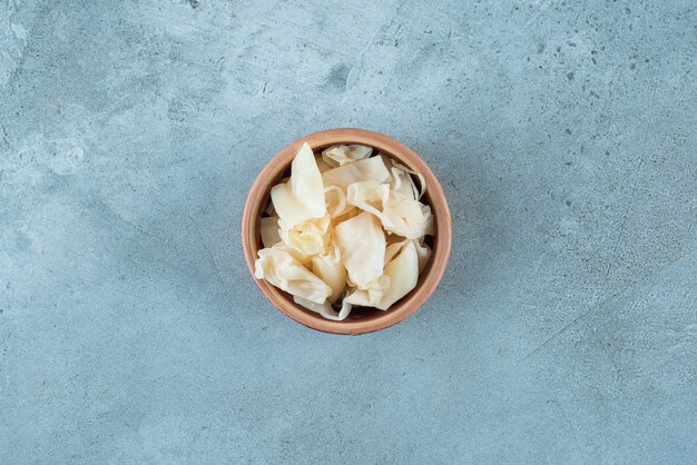 Fermented sauerkraut with carrots in a bowl, on the blue table. 