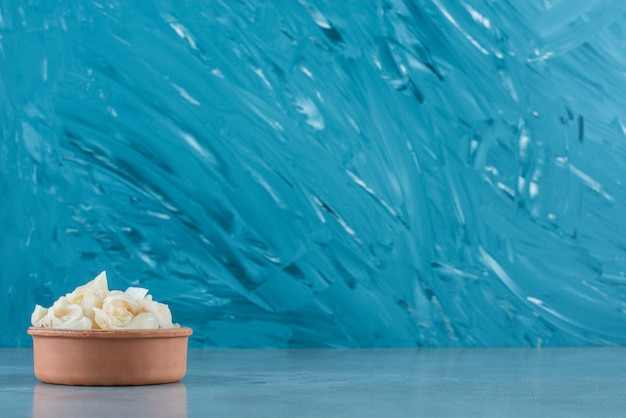 Fermented sauerkraut with carrots in a bowl, on the blue table. 