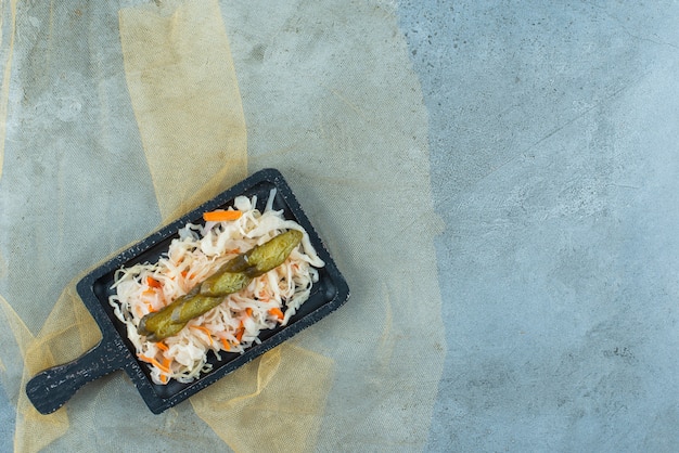 Fermented sauerkraut with cucumber on a board on a tulle , on the blue table. 