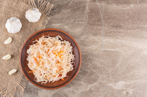 Fermented vegetables sauerkraut placed on stone table.