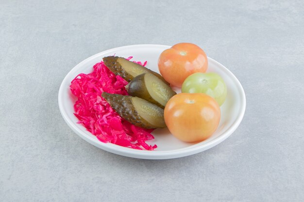 Fermented vegetables and sauerkraut on white plate. 