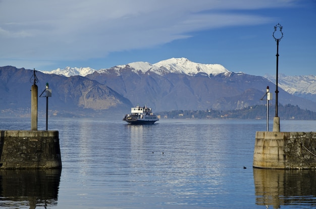 Ferry boat on an Alpine Lake Maggiore with snow-capped mountains in Piedmont, Italy