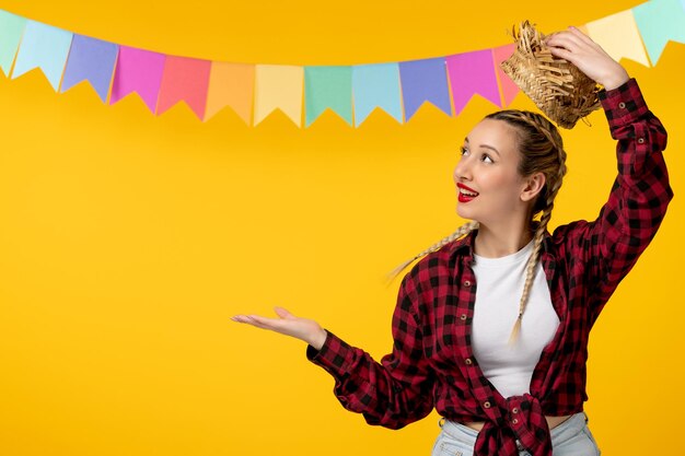 Festa junina blonde cute girl taking straw hat off brazilian festival with colorful flags