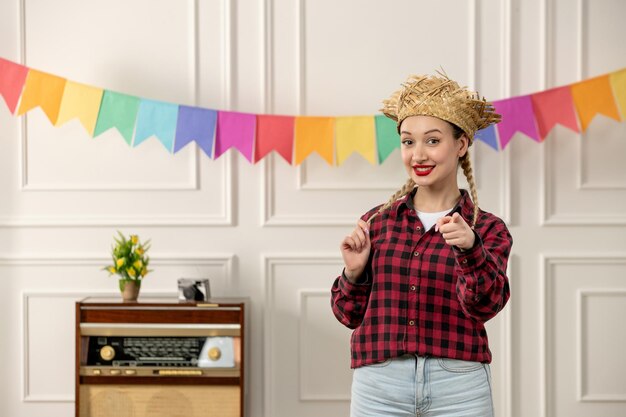 Festa junina cute girl in straw hat brazilian midsummer with radio colorful flags pointing front