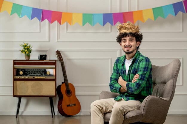 Festa junina cute young guy in straw hat with retro radio and colorful flags crossing hands