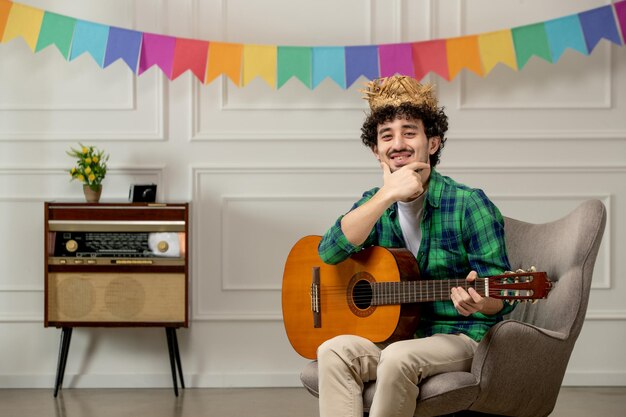 Festa junina cute young guy in straw hat with retro radio and colorful flags holding guitar