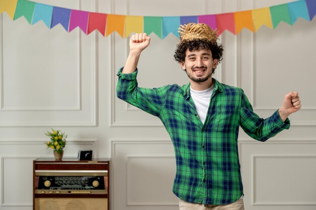 Festa junina cute young guy in straw hat with retro radio and flags dancing happily