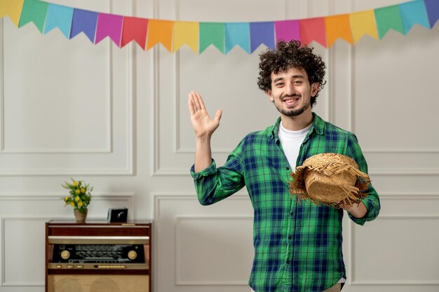 Festa junina cute young guy taking off straw hat with retro radio and colorful flags