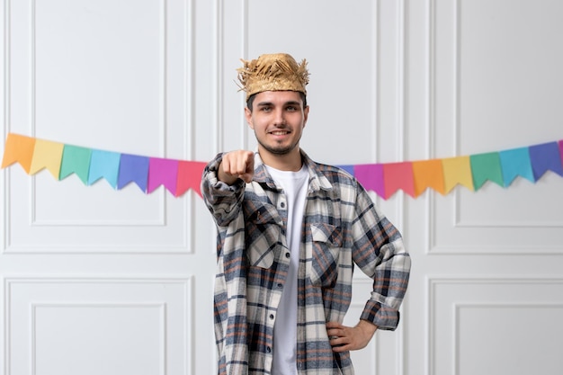 Foto gratuita festa junina bel ragazzo adorabile con cappello di paglia e camicia che celebra il festival che punta a te