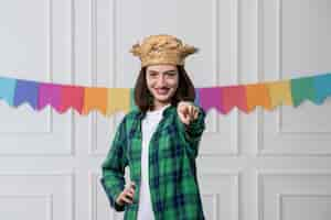 Free photo festa junina pretty young girl with straw hat celebrating brazilian party pointing front