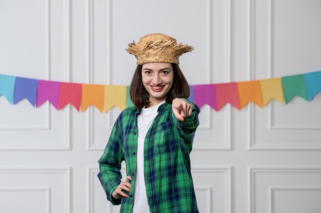 Festa junina красивая молодая девушка в соломенной шляпе празднует бразильскую вечеринку, указывая вперед