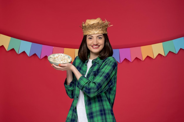 Foto gratuita festa junina in cappello di paglia bruna ragazza carina che celebra il festival brasiliano con popcorn