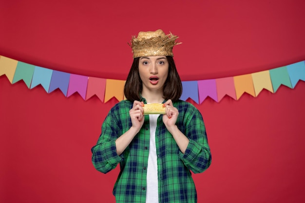 Foto gratuita festa junina che indossa un cappello di paglia ragazza carina che celebra il festival brasiliano che tiene il mais