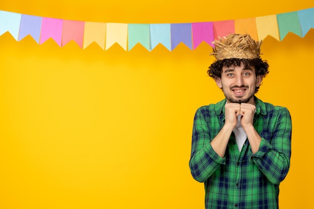 Foto gratuita festa junina giovane ragazzo carino con cappello di paglia e bandiere colorate festival brasiliano eccitato