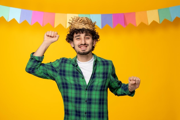 Foto gratuita festa junina giovane ragazzo carino con cappello di paglia e bandiere colorate festival brasiliano eccitato