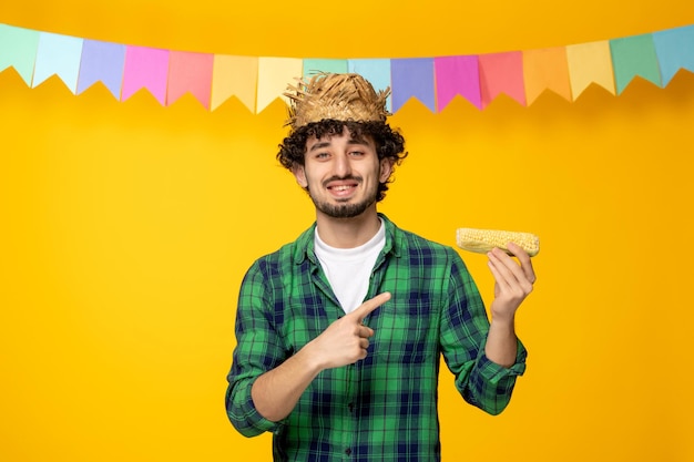 麦わら帽子とトウモロコシを保持しているカラフルな旗ブラジルの祭りでフェスタジュニーナ若いかわいい男