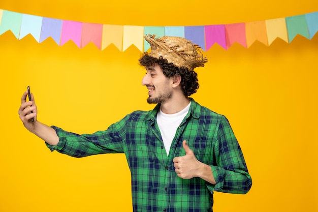 フェスタジュニーナ麦わら帽子とカラフルな旗の若いかわいい男ブラジルの祭りで自撮り