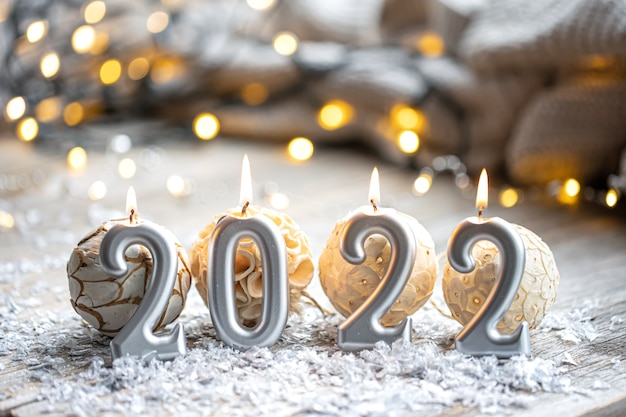 Festive Christmas background with burning candles in the form of the numbers 2022 on a blurred background with bokeh.