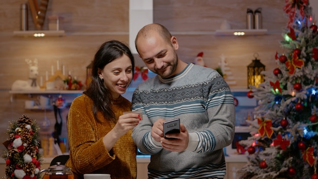 Coppia festiva che compra regali con carta di credito su smartphone