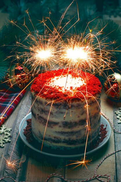花火でお祝いのデザートの誕生日やバレンタインの日の赤いベルベットのケーキ