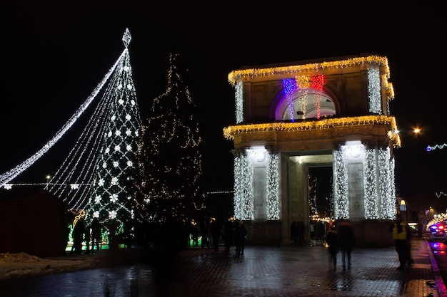 Foto gratuita luci festive e albero di natale vicino all'arco di trionfo