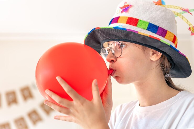 Free Photo a festive girl inflates a balloon on her birthday birthday concept