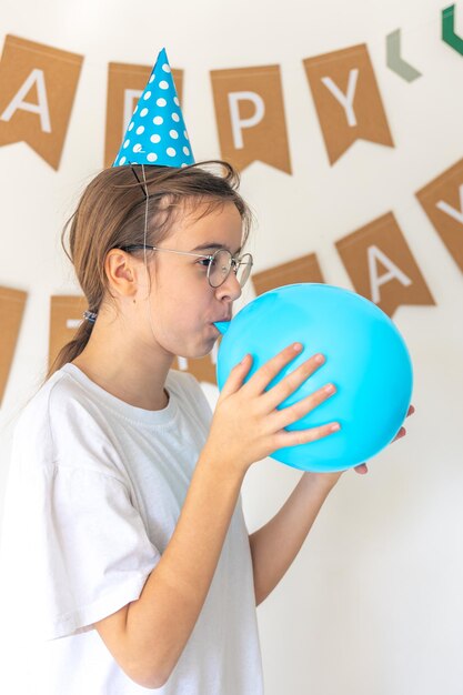 A festive girl inflates a balloon on her birthday